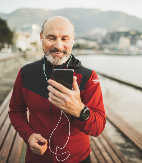 A middle aged man on a beach front pier, looking at his mobile phone A middle aged man on a beach front pier, looking at his mobile phone