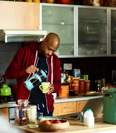 A young man pouring coffee in his kitchen A young man pouring coffee in his kitchen